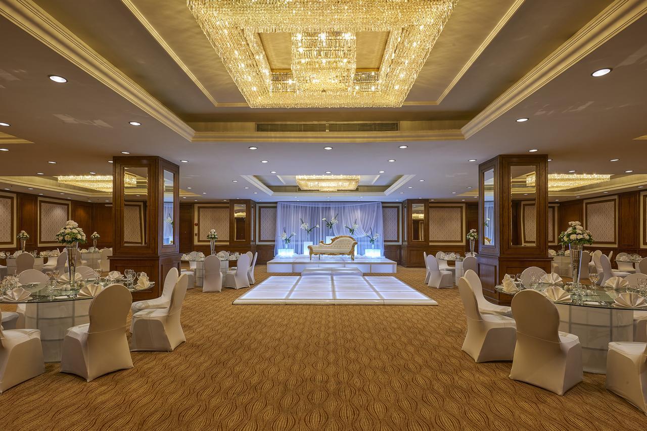 Safir Hotel Cairo Giza Exterior photo The photo shows an elegantly decorated event space. The room features a beautiful chandelier hanging from the ceiling, providing a warm glow. In the center, there is a raised platform that appears to be set up for a ceremony or celebration. Surroundi